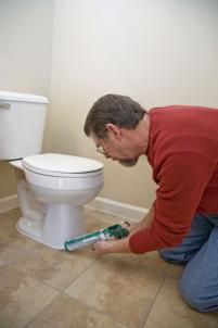 Modesto plumbing contractor caulks a toilet